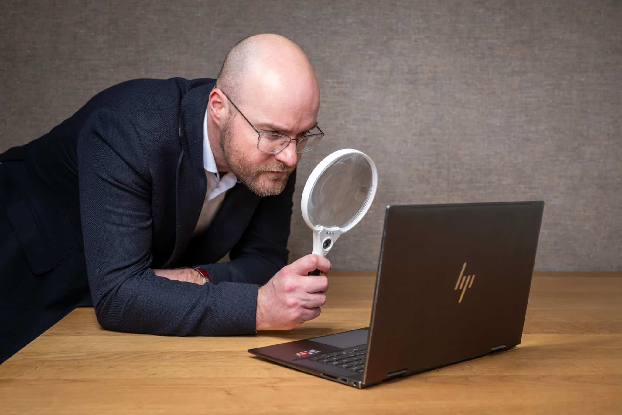 Foto van Pieter. Hij kijkt met de vergrootglas naar een laptop